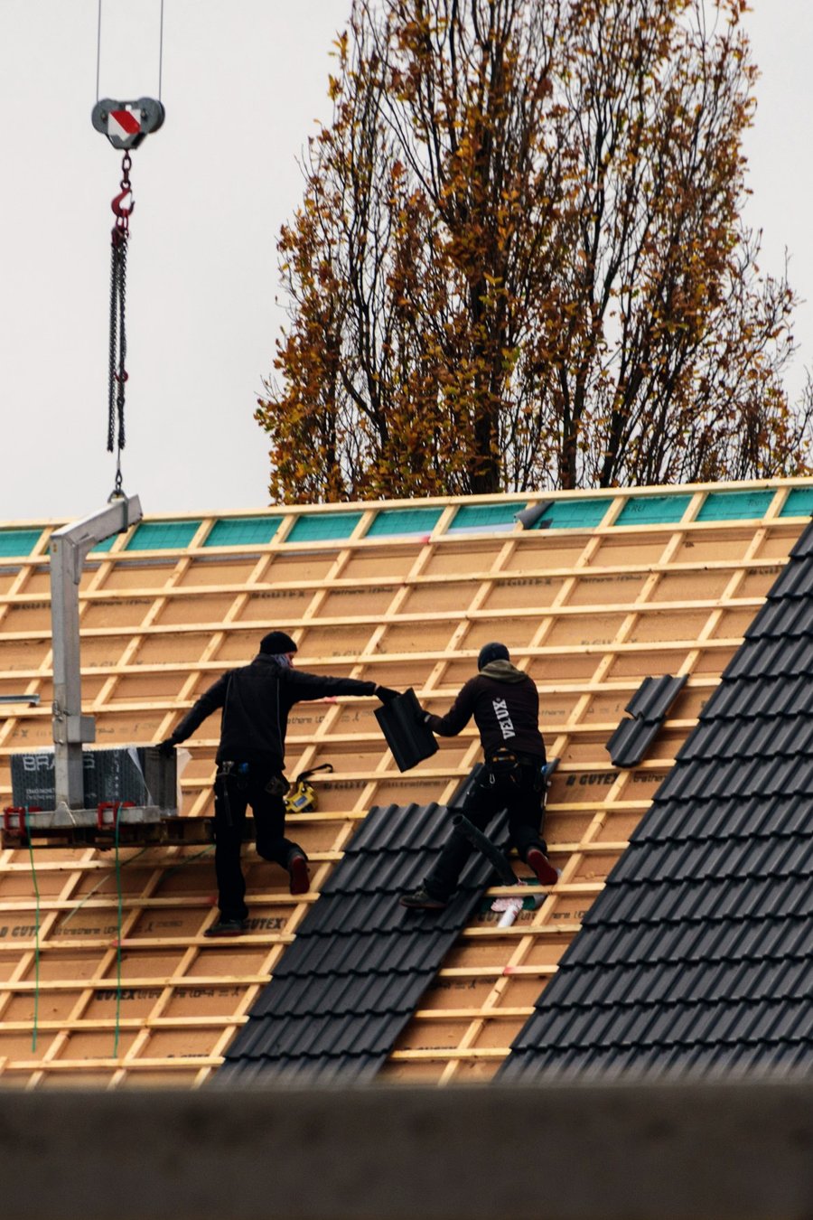 Two roofers laying tiles on a new roof